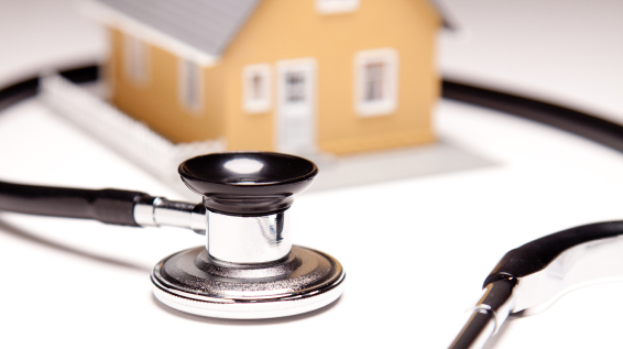 A small house model surrounded by a stethoscope